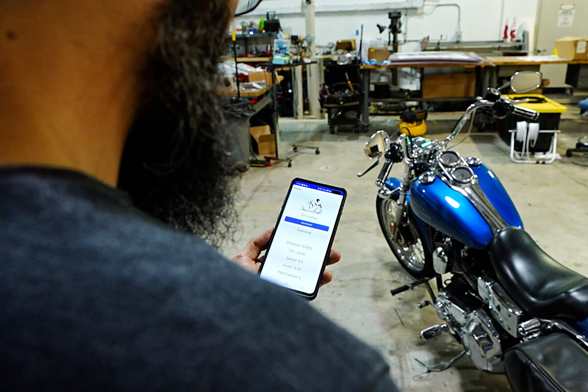 Person looking at application on phone next to motorcycle