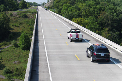 The SOADS F-150 and a police vehicle driving on the Virginia Smart Roads bridge