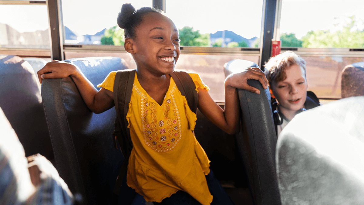 A child with a backpack on a school bus